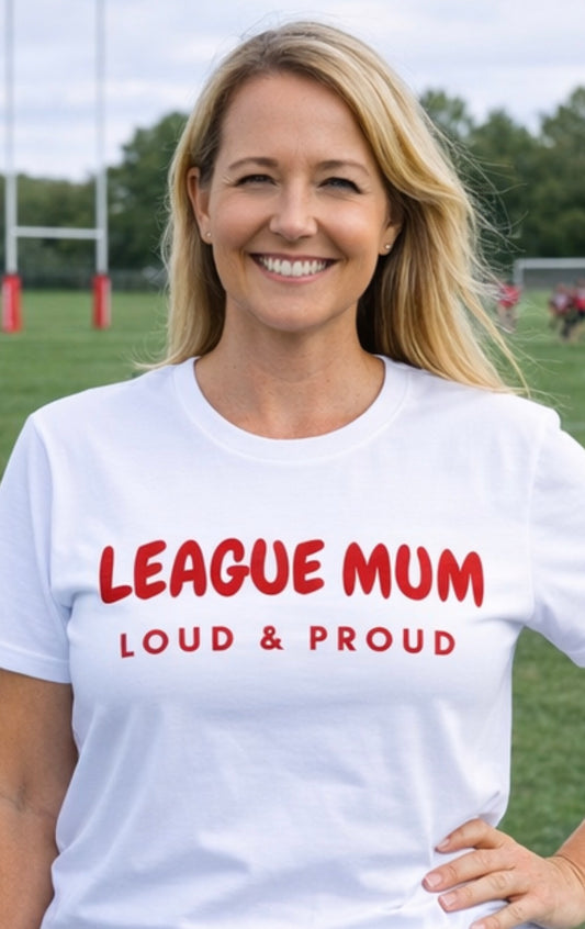 Woman wearing a white t-shirt with 'LEAGUE MUM LOUD & PROUD' text on a sports field.
